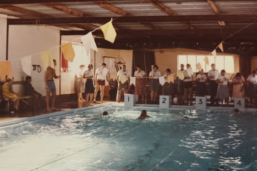 An old photo of people swimming in an indoor pool