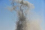 Libyan rebel fighters defiantly raise their weapons after a bomb dropped by an airforce fighter jet explodes