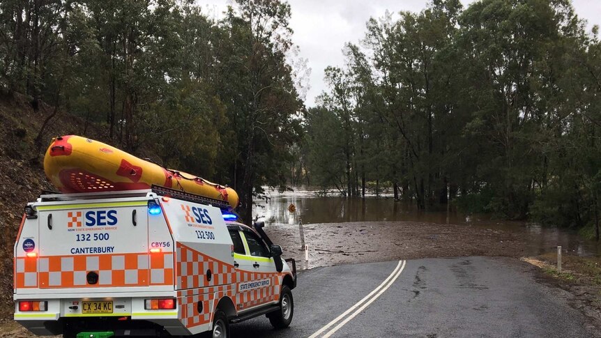 An SES car with a inflated boat on top near a flooded road