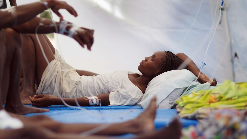 A woman lies on a stretcher with IV lines around her