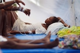 A woman lies on a stretcher with IV lines around her