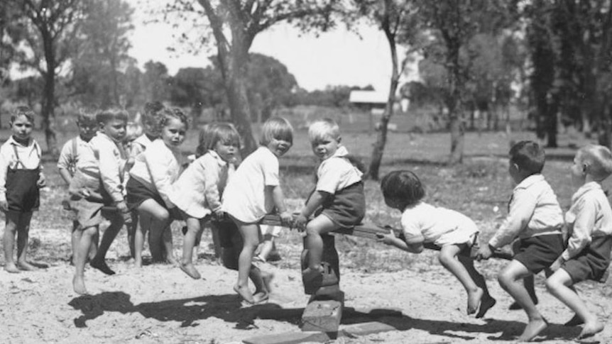 Old photo of Aboriginal children sitting on wooden see-saw