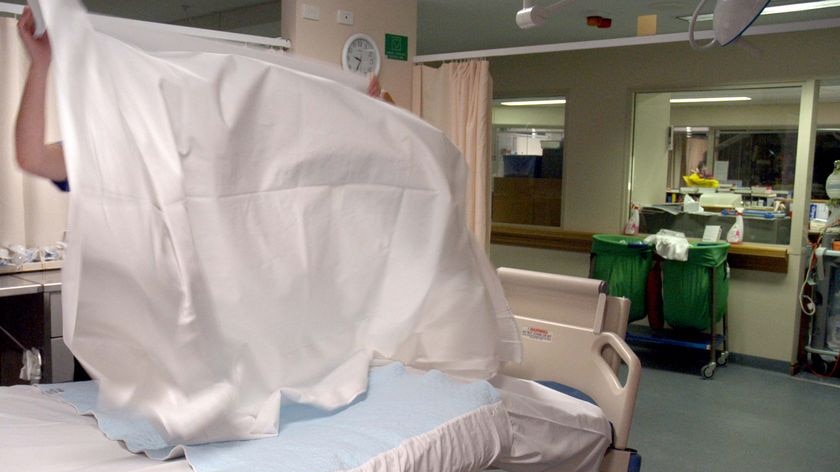 A nurse makes a bed in a hospital ward