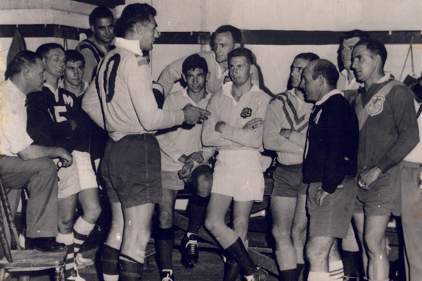 Norm Provan speaks to his St George players inside a dressing room.