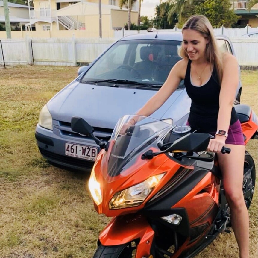 A woman on a motorcycle with a car behind her.