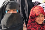 Two females wearing Islamic headdress  look away from the camera as they are photographed.