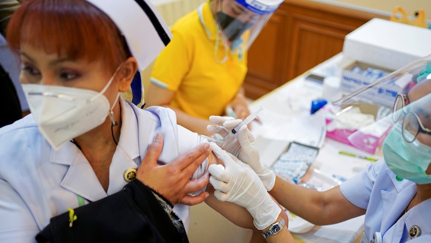 A woman in a nursing uniform received a vaccine in her arm. 