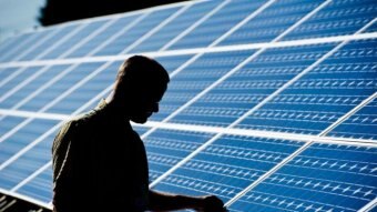 Man assesses solar panels on a roof.