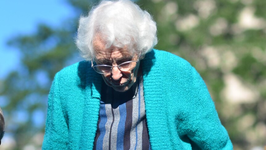 A woman stands as she listens at a special outdoor broadcast of Australia All Over in Brisbane.