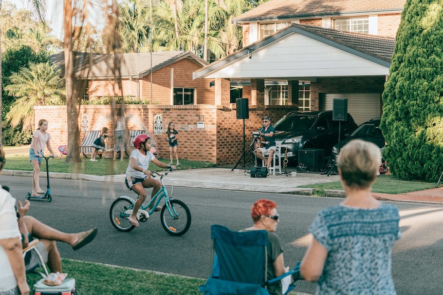 People watch on as Chris Atkinson performs a driveway music gig