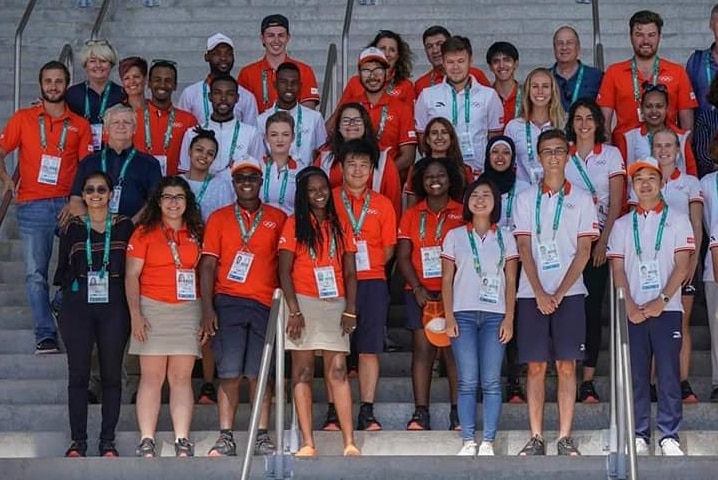 A group of people in uniform stand on steps in several rows - men, women and young reporters from all different countries.