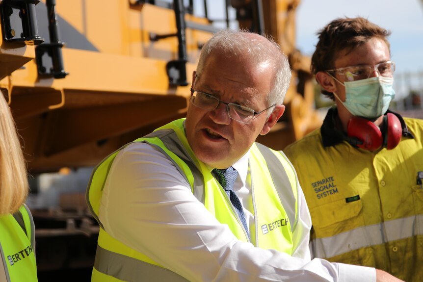 Scott Morrison stands alongside a worker, while wearing a high-visibility vest.