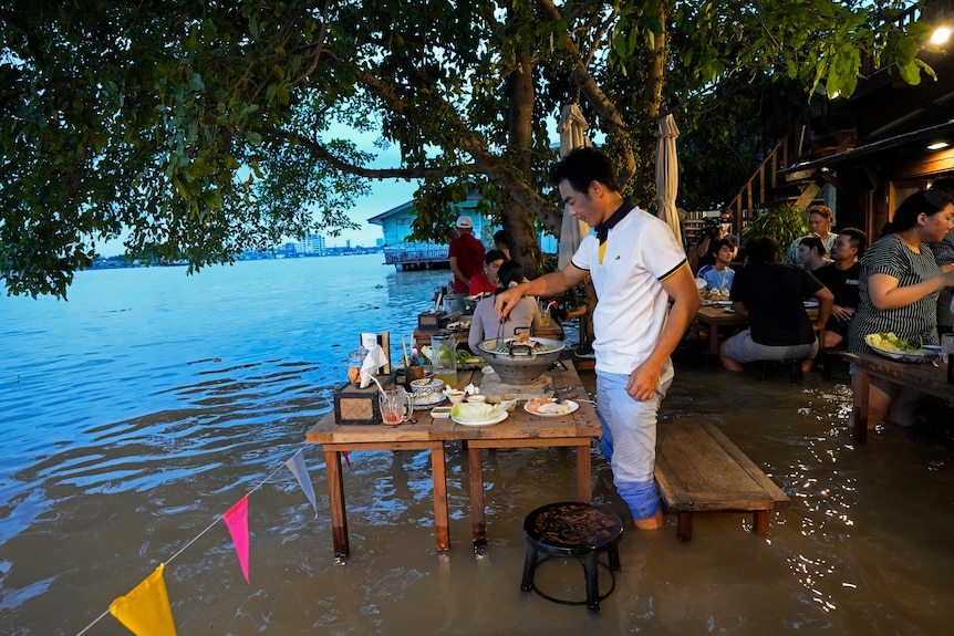 Customers enjoy the flooded riverside cafe