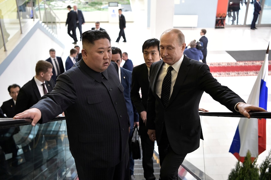 Kim and Putin rest their hands on the railings of an escalator as they ride up together.