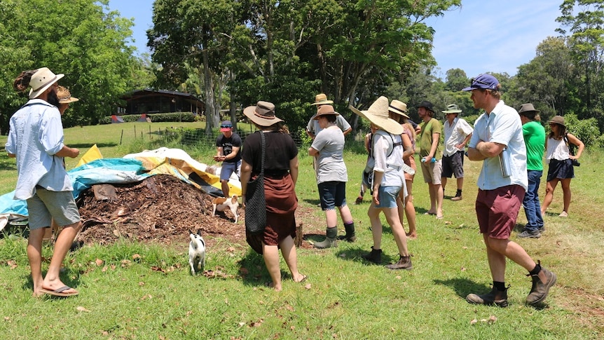 A group of young farmers around a compost pile.