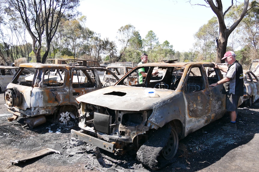 Two men inspecting burnt out car