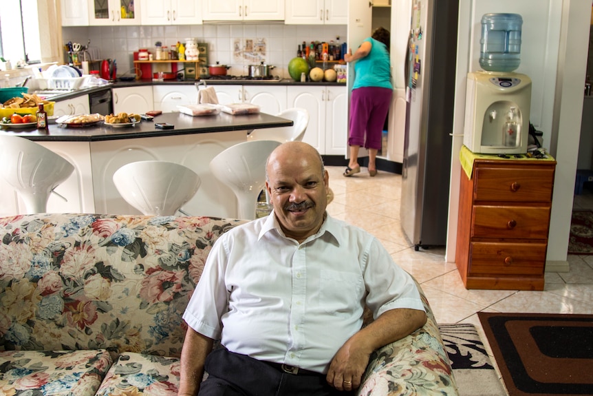Reifat Boutros sits on a couch in his living room