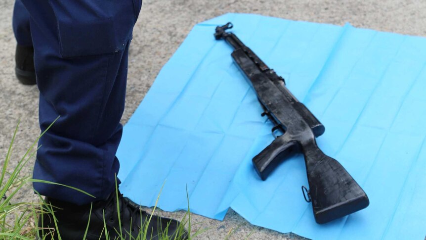 Policeman photographs semi-automatic rifle seized at Punchbowl home