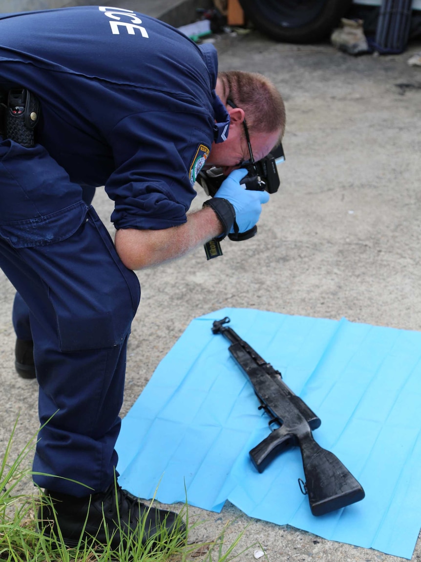 Policeman photographs semi-automatic rifle seized at Punchbowl home