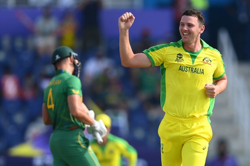 An Australian male bowler pumps his right fist as he celebrates taking a South African wicket.