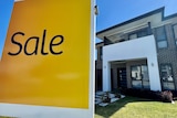 A yellow sale sign advertising a newly built house is on the market.