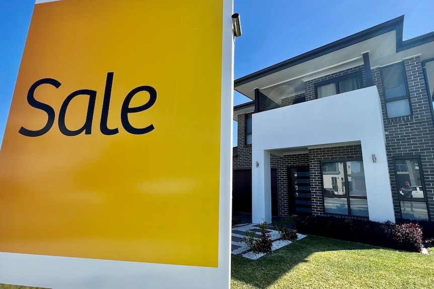 A yellow sale sign advertising a newly built house is on the market.