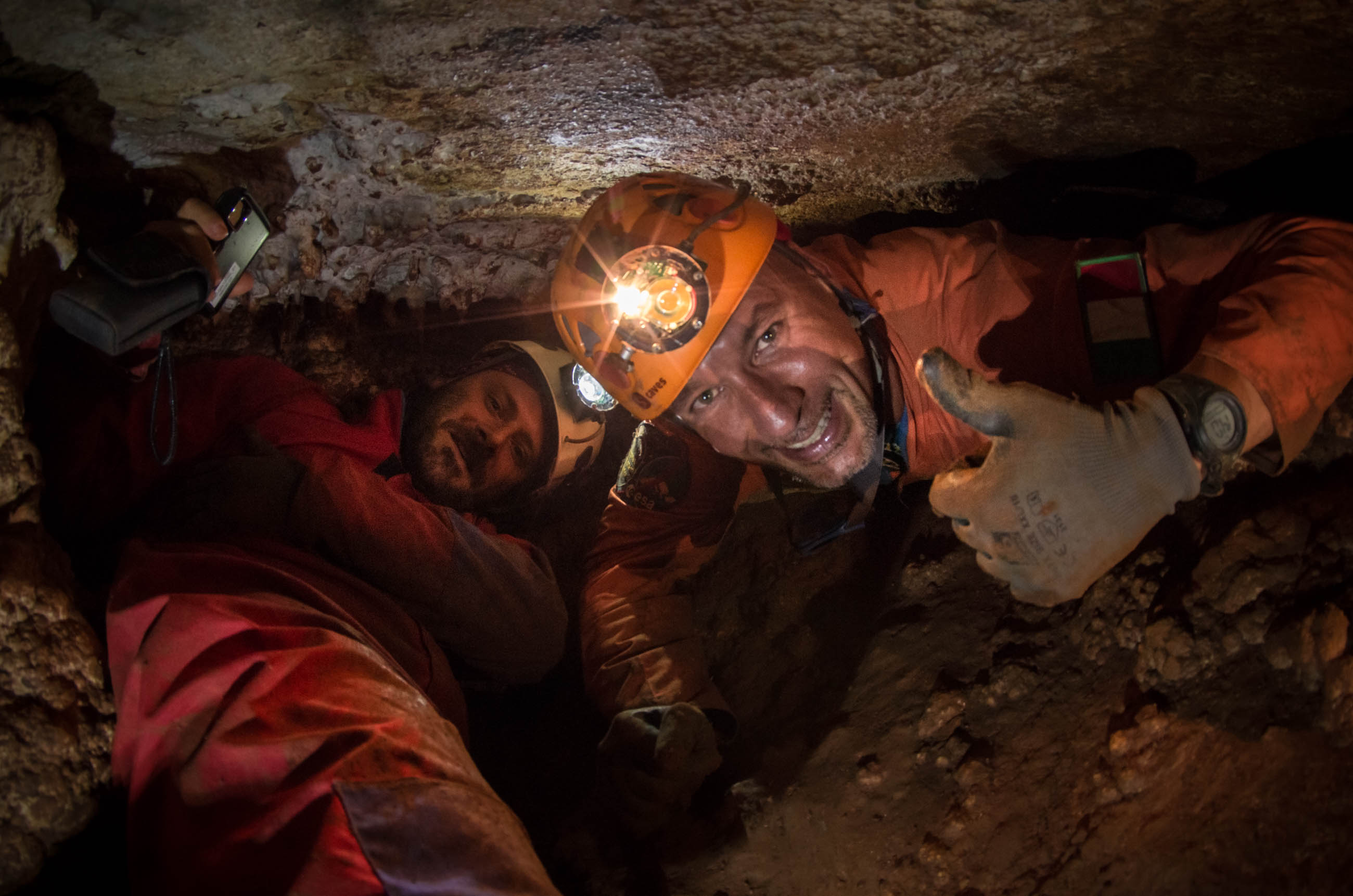 two men with helmets on in a cave.