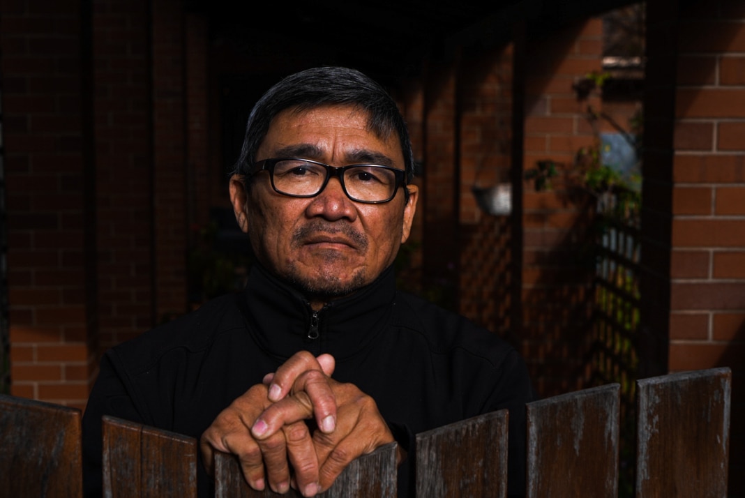 Close-in image of a priest, sitting with his hands clasped