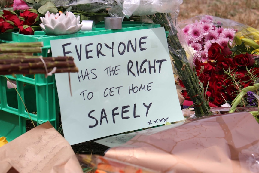 Roses are laid over a milk crate with a sign reading 'everyone has the right to get home safely xxxx'