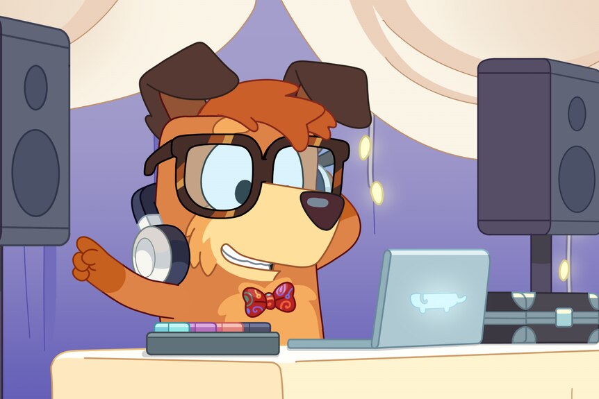 Una imagen fija de Bluey que muestra a Busker como DJ.  Hay un perro largo en la parte trasera de su computadora portátil.