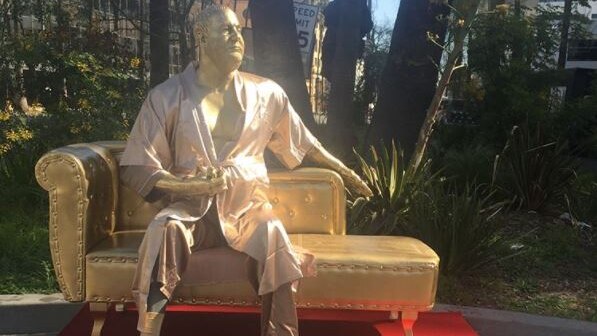 A gold figure of disgraced Hollywood producer Harvey Weinstein sitting on a golden 'casting couch' clutching an Oscar