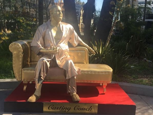 A gold figure of disgraced Hollywood producer Harvey Weinstein sitting on a golden 'casting couch' clutching an Oscar