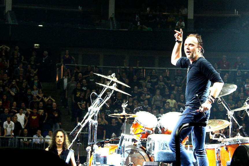 Lars Ulrich raises his hand above his head during a Metallica concert in London.