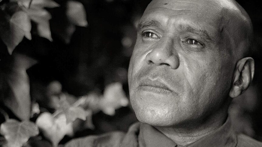 A black and white photo of Archie Roach staring into the distance
