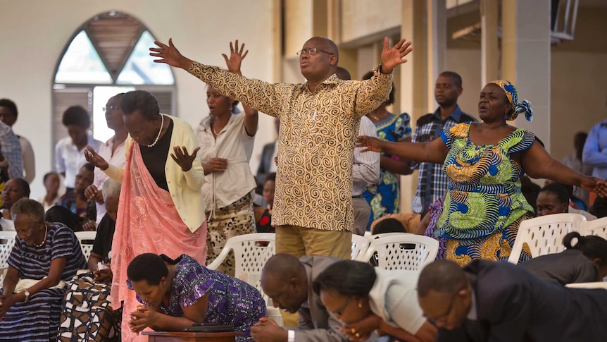 Rwandans sing and pray with their arms raised high at the Evangelical Restoration Church