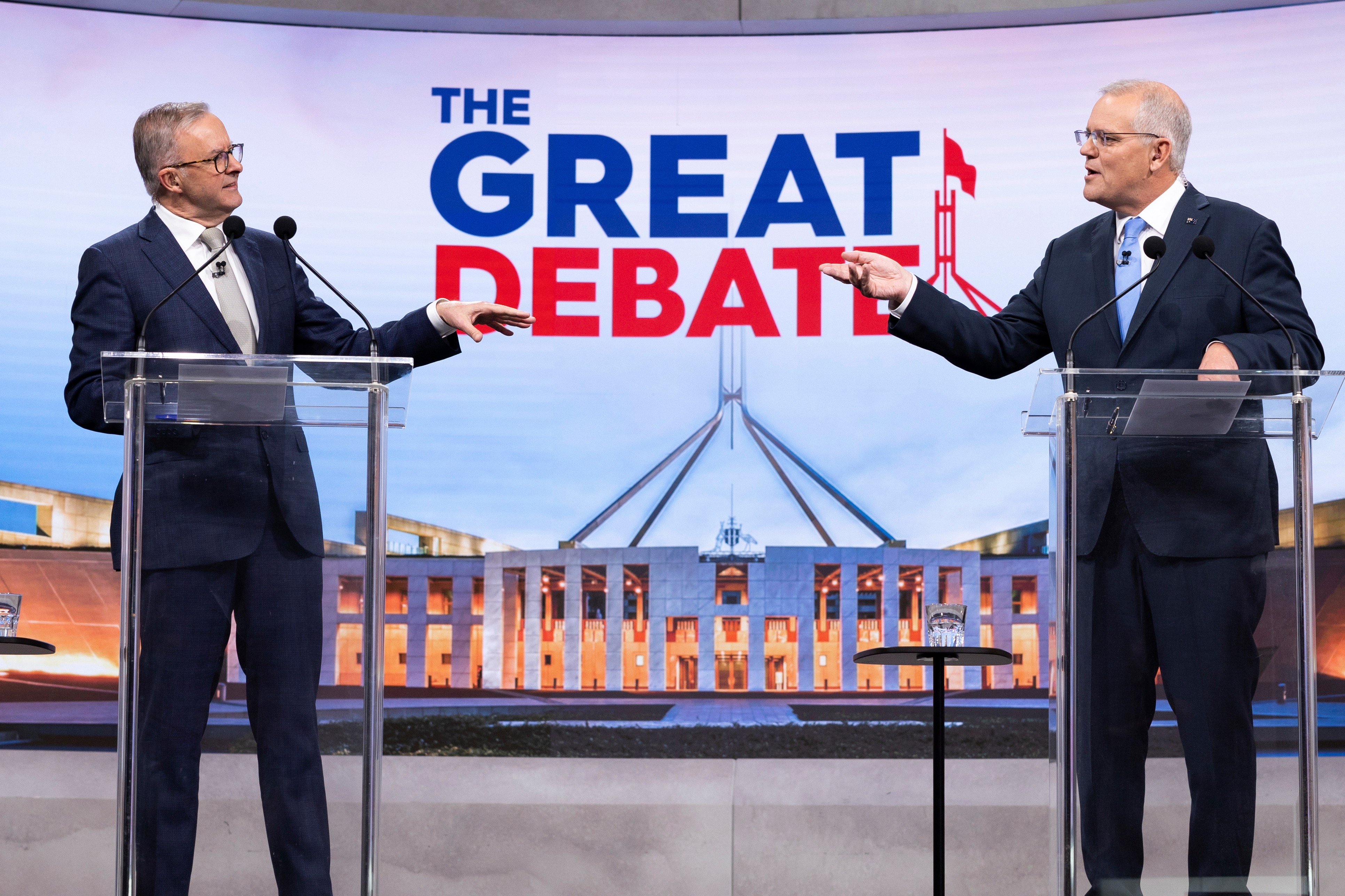 Anthony Albanese y Scott Morrison se señalan mientras debaten en un televisor