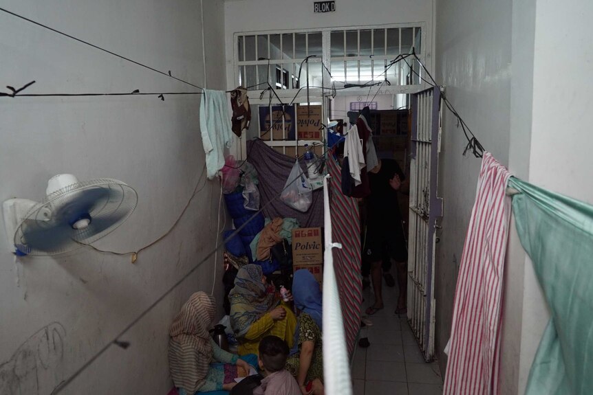 Families use sheets as curtains for privacy at Jakarta Immigration Detention Centre.