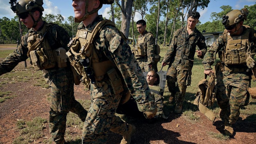 A group of marines carrying one injured soldier.