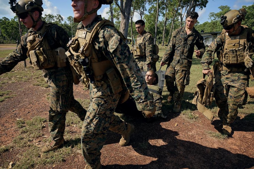 A group of marines carrying one injured soldier.