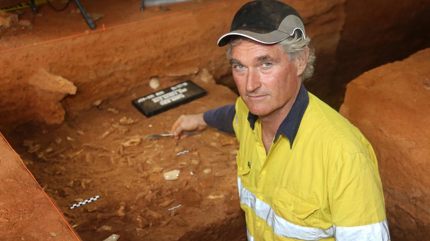 Peter Veth points at items excavated in a cave.