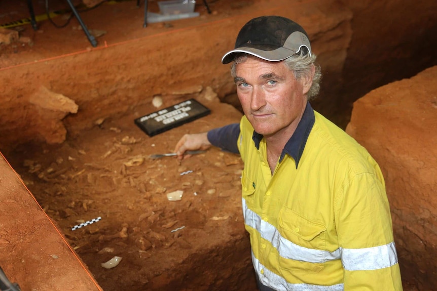 Peter Veth points at items excavated in a cave.