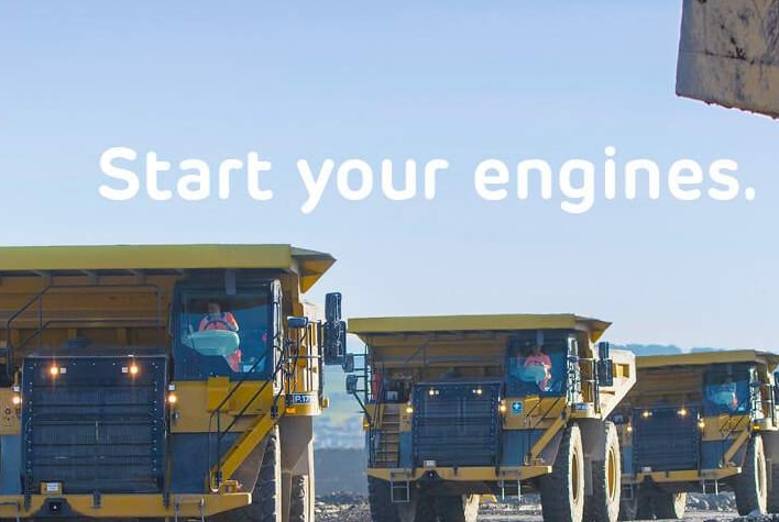 A promotional photo showing a line of mining trucks and the words 'Start your engines'.