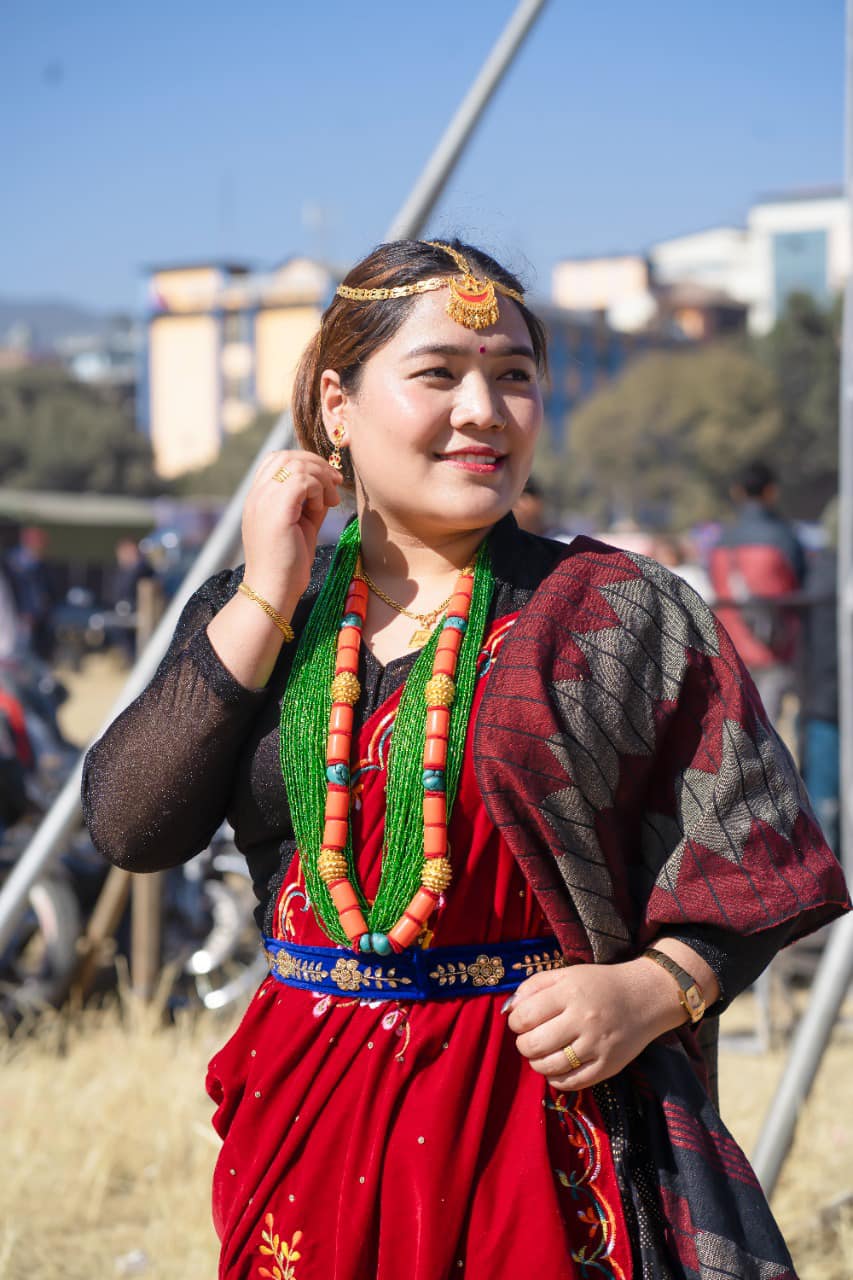 A woman in traditional Nepali dress dances outside.