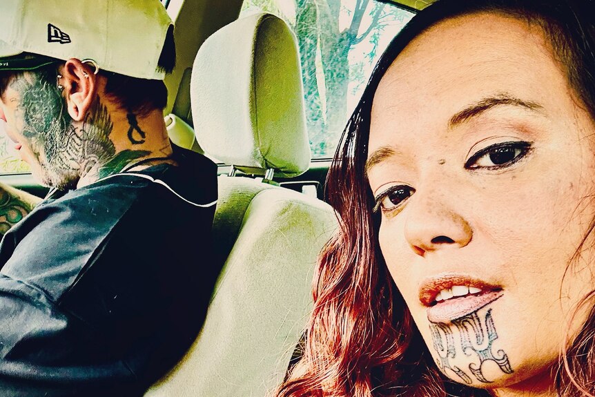 Woman in a car with a tattoo on her chin.