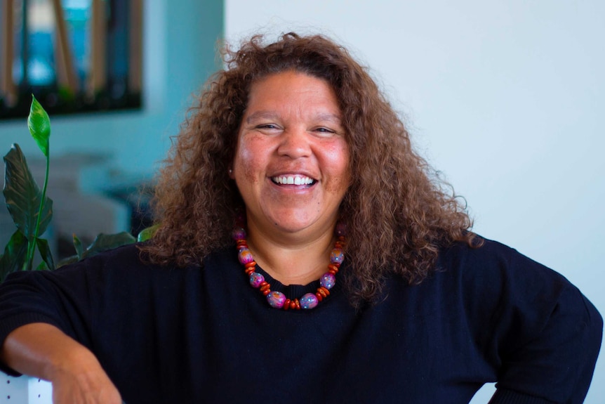 A portrait of Karina Lester in an office wearing a blue sweater.