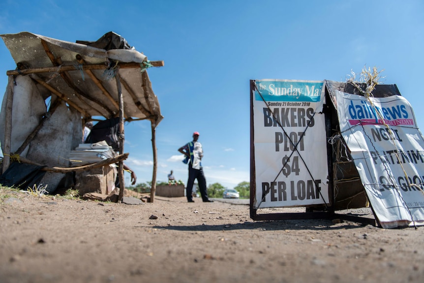 a man stands behind newspaper signs