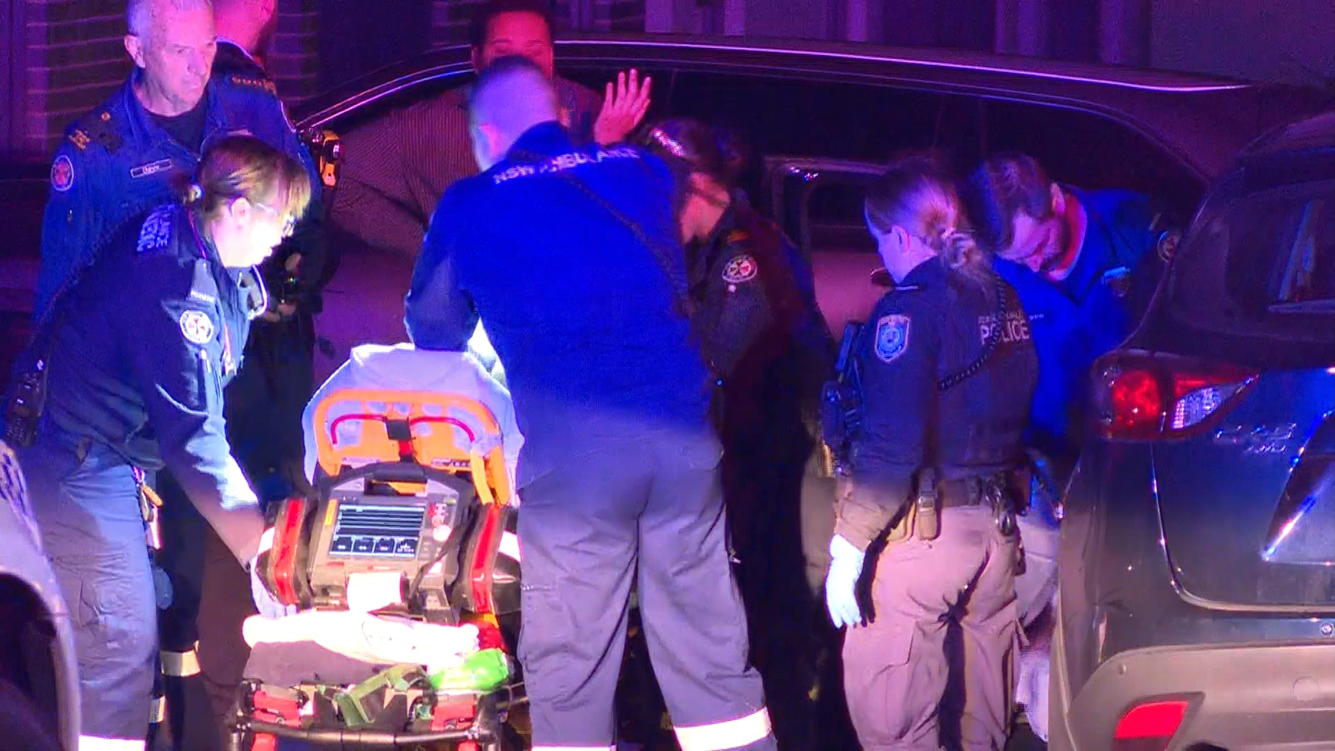 A man on a stretcher being wheeled into the back of an ambulance.