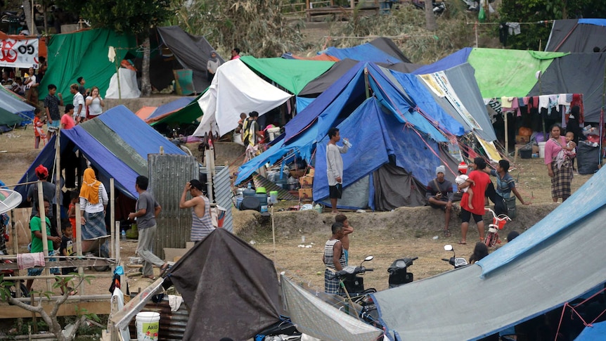 Villagers gather at a temporary shelter after fleeing their damaged village