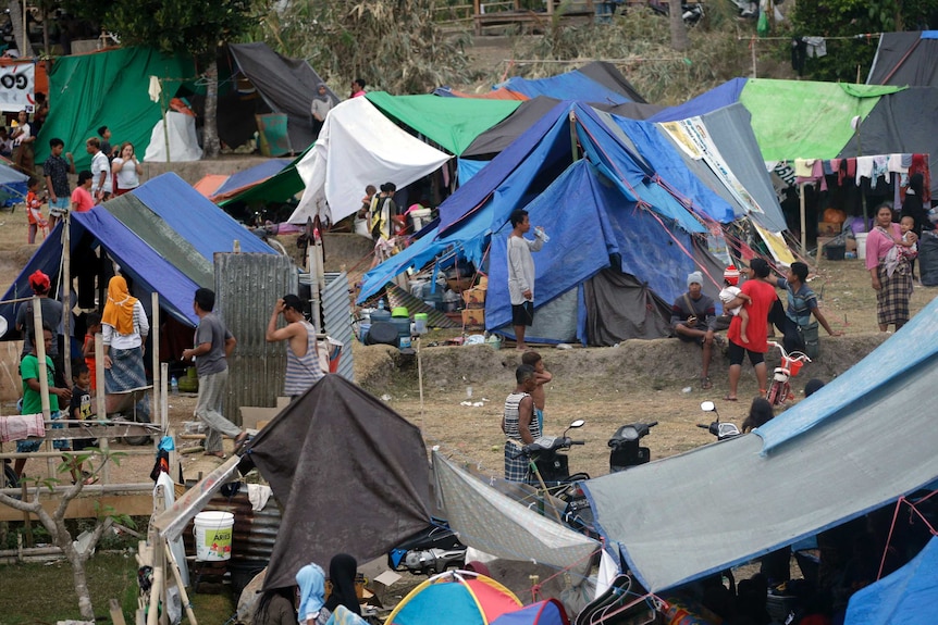 Villagers gather at a temporary shelter after fleeing their damaged village