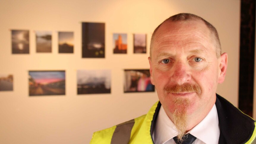 Glenn Luttrell standing in the exhibition in Moonah.